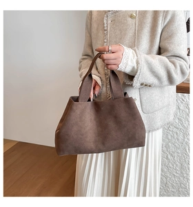 Detail of a dark brown suede tote bag featuring a minimalist trapezoid design and soft texture