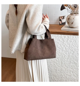 Detail view of large dark brown suede tote bag carried by model in casual lifestyle setting