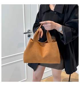 Detail of tan suede tote bag featuring a minimalist silhouette and wide handle design