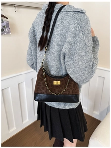 Detail der Schultertasche mit Leopardenmuster Goldkette und Drehverschluss am Pullover