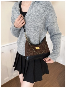 Detail der Schultertasche mit Leopardenmuster und goldenem Drehverschluss am grauen Outfit