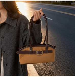 Close-up of vintage brown suede shoulder bag with deep leather strap and metal buckle