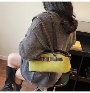 Detail of green suede shoulder bag with brown leather strap and gold buckle accent