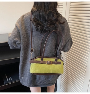 Close-up of green suede shoulder bag with brown leather trim and metal buckle detail