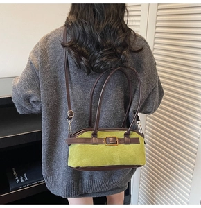 Detail view of vintage green suede handbag with brown leather straps worn on shoulder