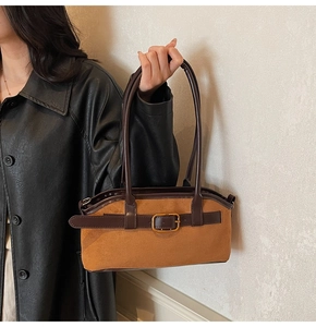 Close-up of brown suede shoulder bag featuring a vintage leather strap and gold metal buckle