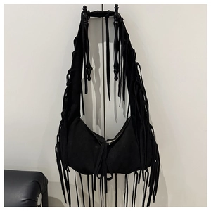 Détail du sac croissant en daim noir avec de longues franges et accents bohèmes
