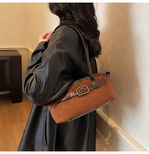 Detail of suede hobo bag with gold buckle hardware and premium leather shoulder strap
