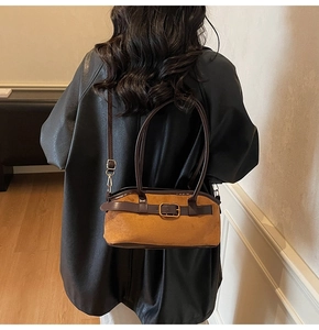 Brown suede shoulder bag with leather handle and gold buckle detail shown on model