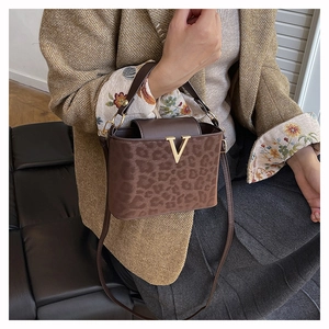 Détail du sac léopard avec boucle en V dorée et poignée en cuir marron élégante