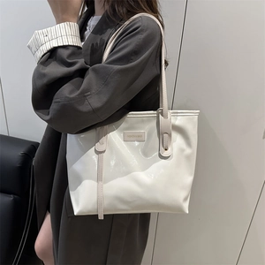 Chic white patent leather tote bag with shoulder strap shown on a model for daily use