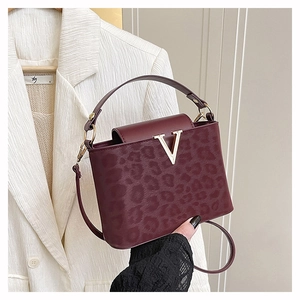 Détail du sac bandoulière bordeaux avec texture léopard gaufrée et boucle en V dorée
