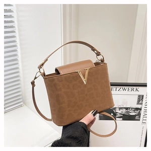 Détail du sac seau marron avec logo V doré et texture en cuir grainé de haute qualité