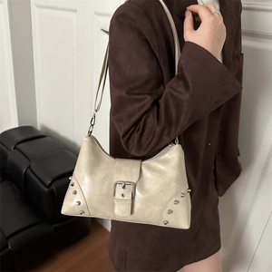 Cream chic rivet tote bag with silver buckle worn by a model in a modern room