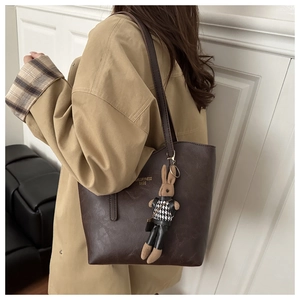 Detail of dark brown leather tote bag with gold lettering and cute bunny pendant charm