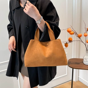 Minimalist camel suede tote bag with large capacity, shown handheld by a model