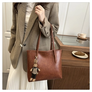 Detailed view of a vintage brown tote bag with a cute rabbit doll charm and smooth leather