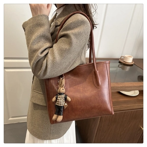 Close-up of vintage brown tote bag with leather texture and cute rabbit charm pendant