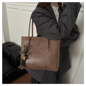 Detail of taupe tote bag with side stitching and a plaid bunny charm for office style