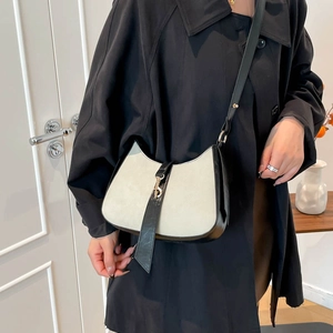 Minimalist grey suede half-moon crossbody bag with black leather trim and metal clasp