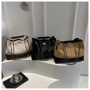 Close-up of quilted chain tote bags in white, black, and khaki on a minimalist stand