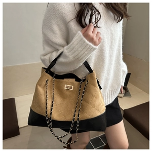 Detail of contrast-panel tote bag featuring diamond-quilted pattern and gold chain strap