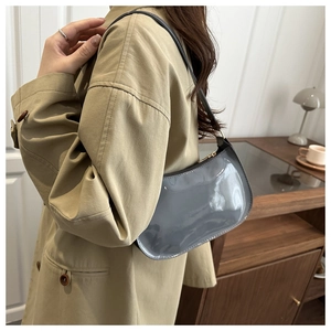 Close-up of a stylish grey patent leather crescent bag on a shoulder for chic daily use
