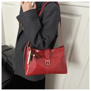 Détail du sac à bandoulière en cuir bordeaux avec breloque ethnique et fermoir métallique