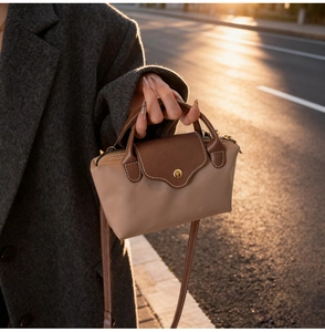 Close-up of khaki and brown nylon mini bag with leather handles and gold snap button