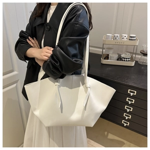 Gros plan du sac cabas plissé blanc avec texture litchi porté à l'épaule par un mannequin