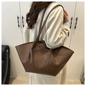 Détail d'un grand sac cabas en cuir marron avec des nœuds élégants sur la bandoulière