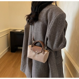 Detail of a minimalist mini nylon crossbody bag with contrast leather handles and flap