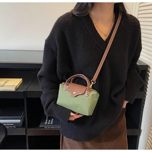 Detail of green nylon crossbody bag with brown leather flap and golden snap closure