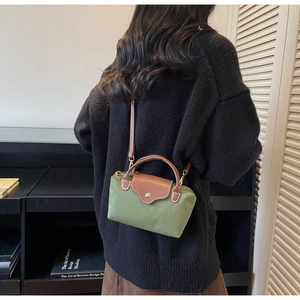 Mini green nylon crossbody bag with brown leather flap shown on a model for size perspective