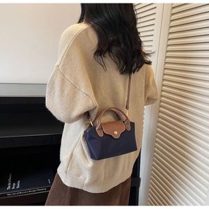 Detailed view of two-tone nylon crossbody bag with leather handles shown on a model