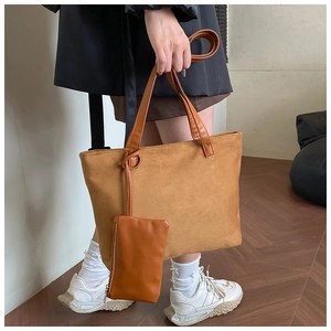 Close-up of camel suede tote bag set featuring smooth leather handles and inner pouch