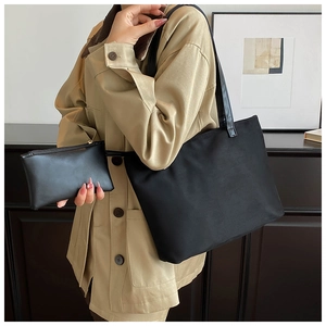 Detail of minimalist black tote bag set with matching small pouch on a shoulder strap