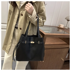 Détail du sac cabas en cuir noir mat avec fermoir métallique et cordon de serrage