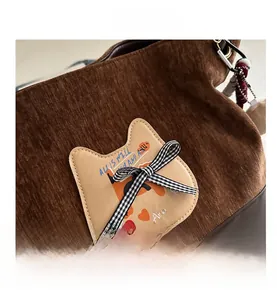 Détail du sac cabas en velours marron avec écusson chat, nœud vichy et logo en cuir