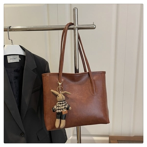 Brown vintage tote bag detail with houndstooth bunny charm on a minimalist stand