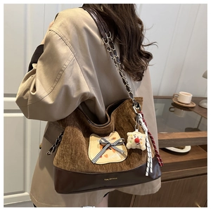 Détail du sac en velours côtelé marron avec patch chat, nœud et porte-clés en peluche