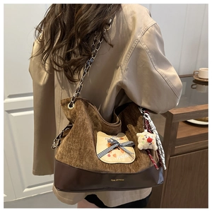 Vue détaillée du sac cabas en velours marron avec breloque peluche et chaîne sur modèle