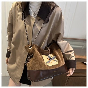 Détail du sac en velours côtelé marron avec écusson chat et bandoulière en chaîne dorée