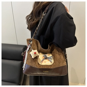 Détail du cabas en velours côtelé marron avec patch chat et porte-clé ours porté