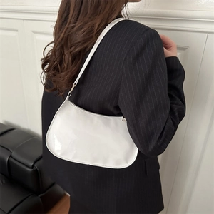 Chic white patent leather half-moon shoulder bag styled with a black striped blazer