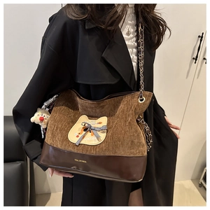 Détail du sac fourre-tout en velours côtelé marron avec écusson chat et bandoulière chaîne