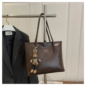 Detail of dark brown tote bag with leather texture and cute plaid bunny charm