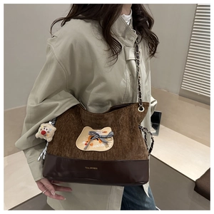 Détail du sac cabas en velours côtelé avec écusson chat et bandoulière en chaîne dorée