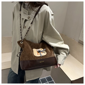 Détail du sac cabas en velours marron avec écusson chat et bandoulière chaîne