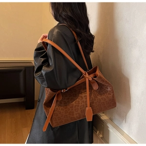 Detail of leopard print tote bag with orange leather handles and geometric charm